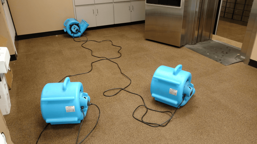 Air movers drying water-damaged carpet at a commercial property in Midland, TX