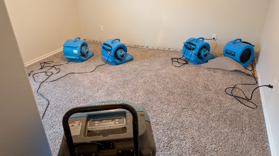Air movers drying water-damaged carpet in a Midland, TX property